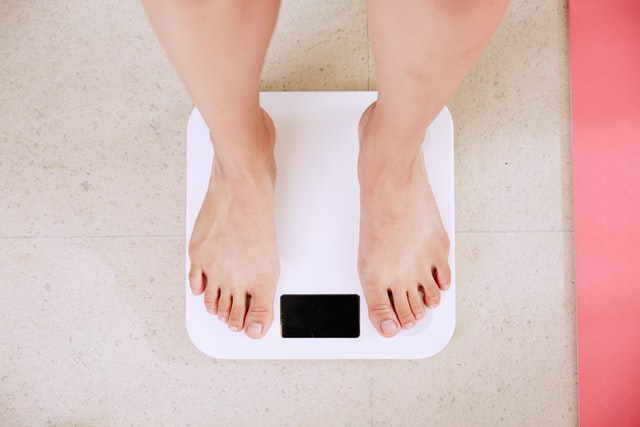 woman on weighing scale checking her weight gain due to kidney failure