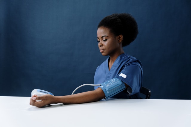 black woman nurse checking her blood pressure with microlife monitor