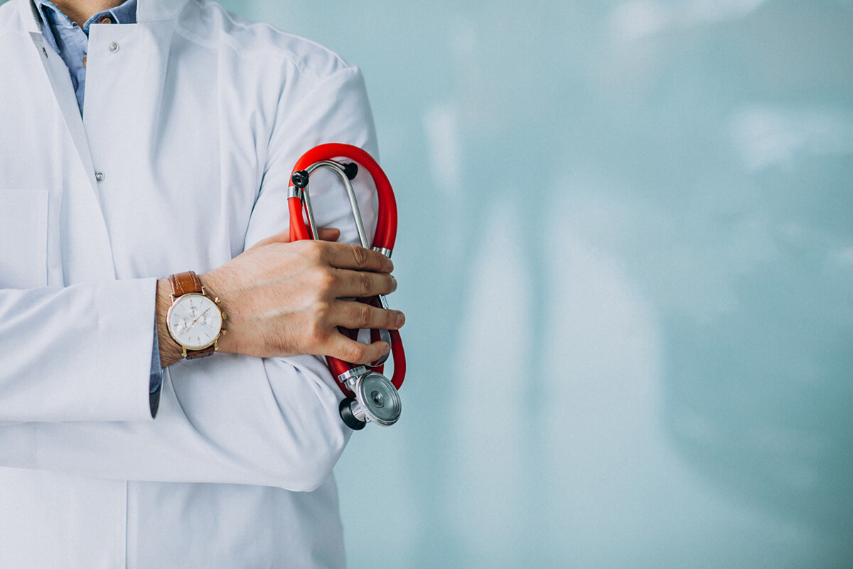 female doctor holding a red stethoscope in a hospital ward