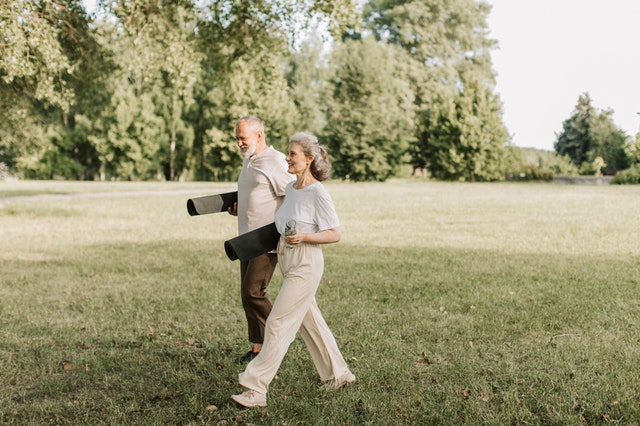 elderly senior retirees walking while holding yoga mats staying active and hydrated in old age