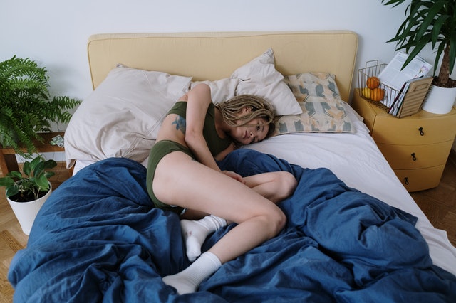 sick woman laying in bed due to prolonged anorexia