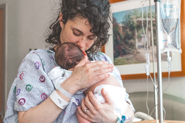 new mother holding her newborn preemie with skin to skin kangaroo care