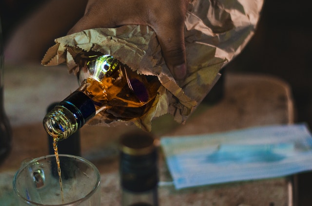 brown paper bag with whiskey pouring over a glass