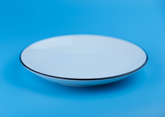 empty ceramic plate one a blue background symbolising anorexia nervosa