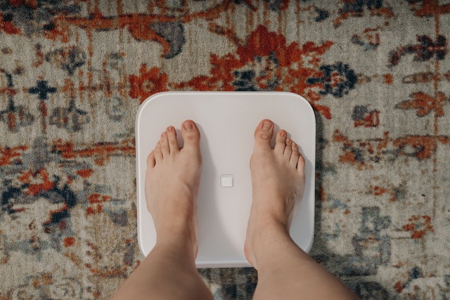 standing on wireless body weight machine to assess weight gain from hormonal issues