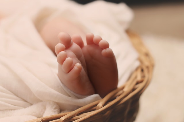 cute newborn feet draped in comfy cotton blanket