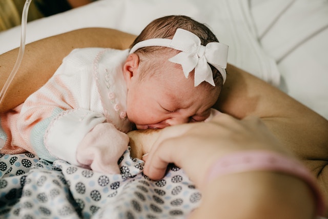 beautiful baby girl breastfeeding with new mom to prevent newborn jaundice