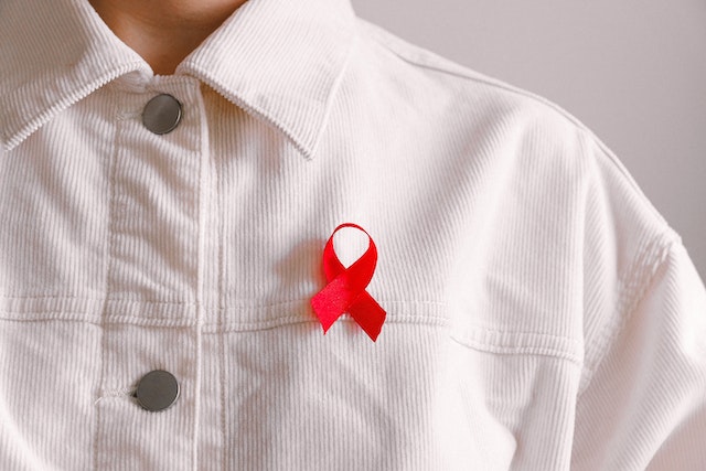 Man wearing white shirt HIV awareness red ribbon