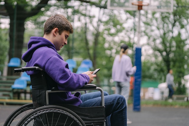 Young man sitting in a wheelchair using his mobile phone