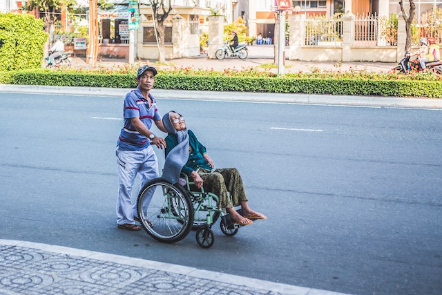 Elderly woman in Asia in a wheelchair ging on a stroll with her son