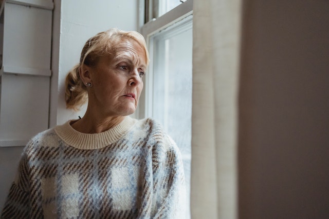 Middle aged woman looking out a window with great concern for her kidney failure diagnosis